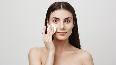 Mladá žena čistí pleť
